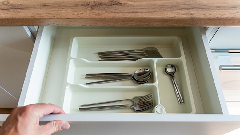 person opening silverware drawer