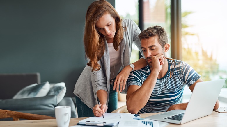 Woman hovers over a man's shoulder discussing finances