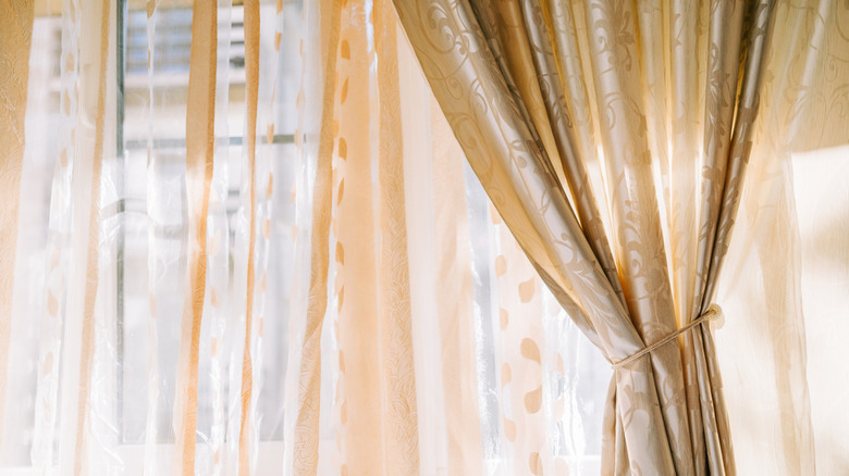 Gold curtains and sheers over a window.