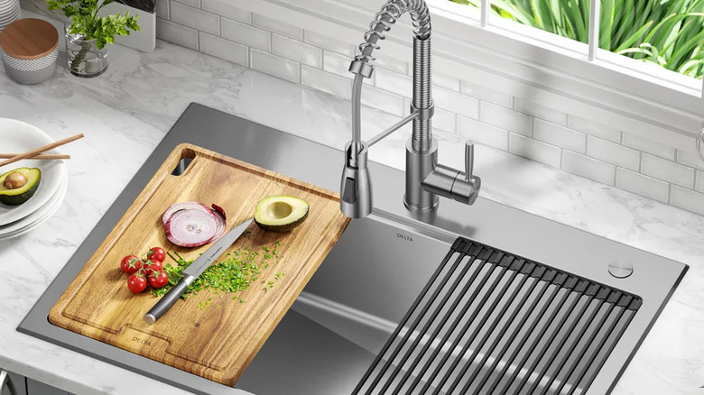 The Delta Workstation Sink installed in a kitchen with accessories like a cutting board and a strainer