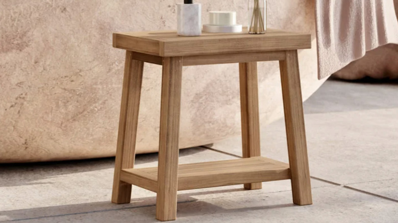 A loveTEAK bench in a bathroom with decor items on top
