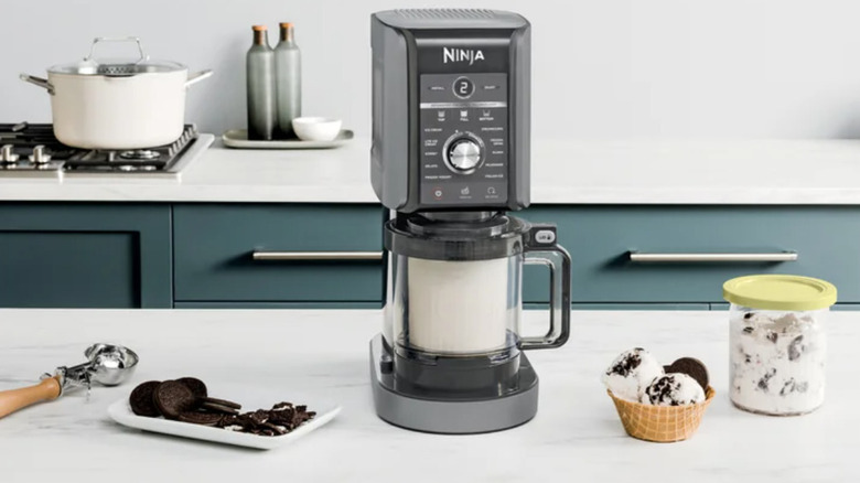 The Ninja CREAMi Deluxe on a kitchen countertop ice cream and cookies