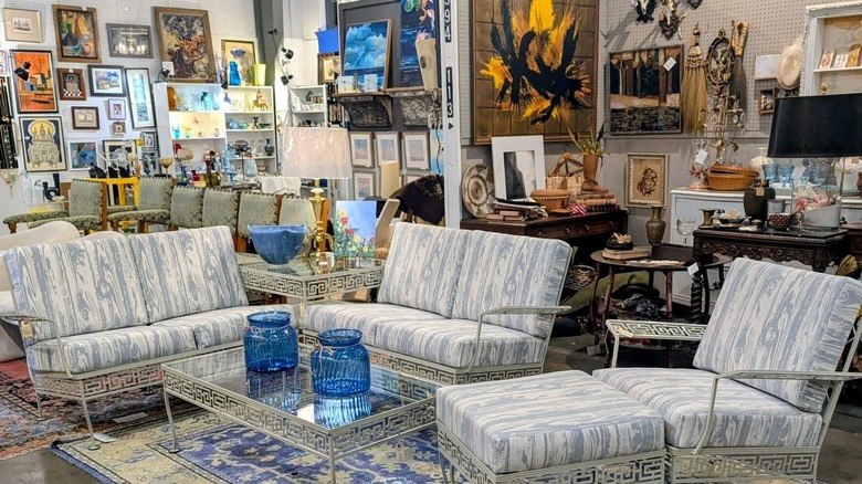 A furniture set, vases, artwork, and lamps on display at a thrift store