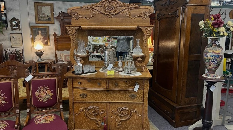 An antique two part sideboard holding silver and glassware