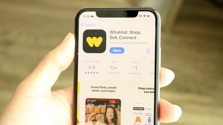 A hand holding a phone and downloading the Whatnot app