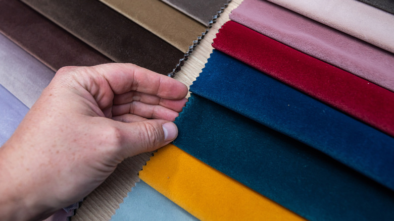 A person touching swatches of velvet fabric.
