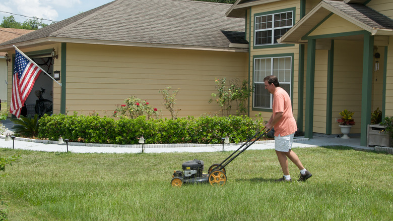 a homeowner mowing the lawn in front of the house