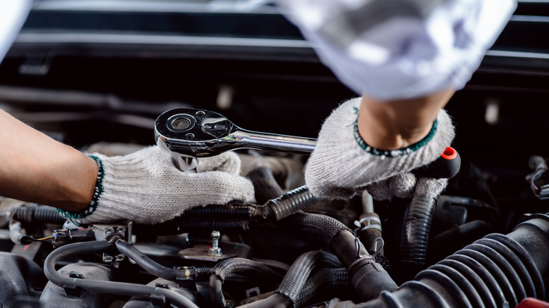 A man using a socket wrench while working on an engine