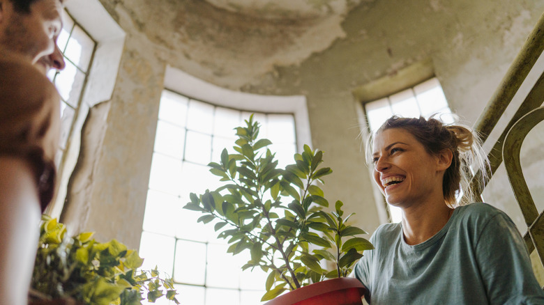 person carrying potted plant indoors