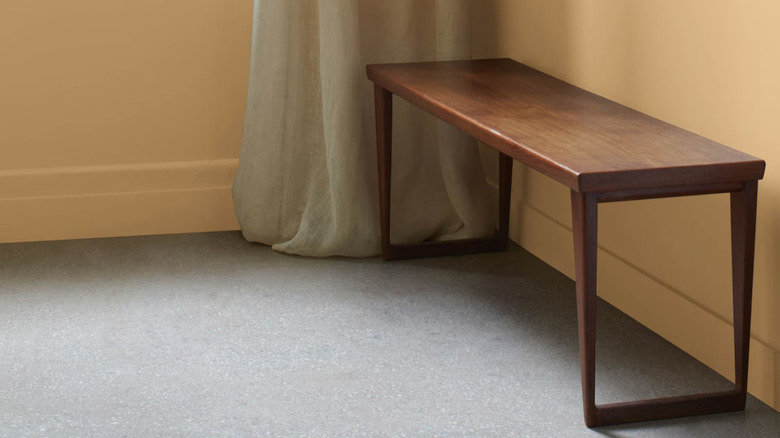 A walnut wood bench and linen curtains in a room with caramel brown walls