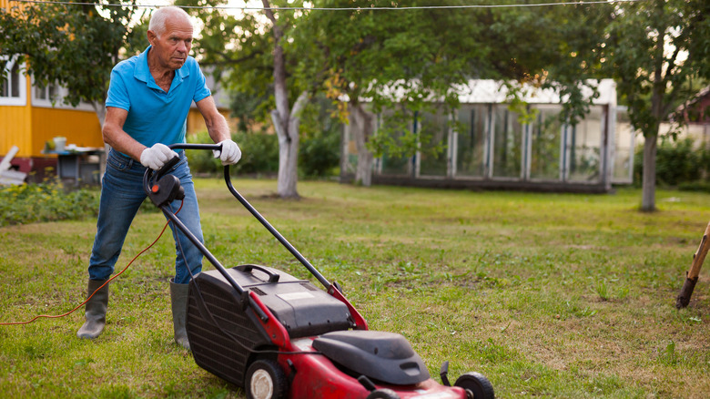 Determined man pushing mower