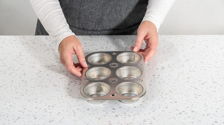 person holding a muffin tin