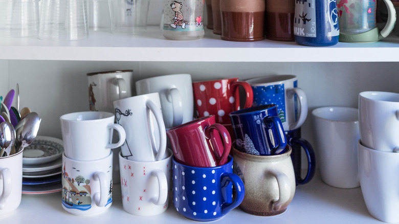 A bunch of mugs crammed on kitchen shelf