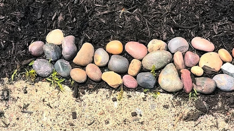 Close-up of the river rocks placed neatly along the border of a mulched garden bed