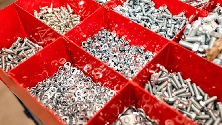 A red metal organizer full of nuts, bolts, and washers