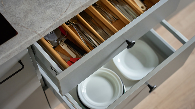 Wood organizers sort utensils and plates in gray deep kitchen drawers.