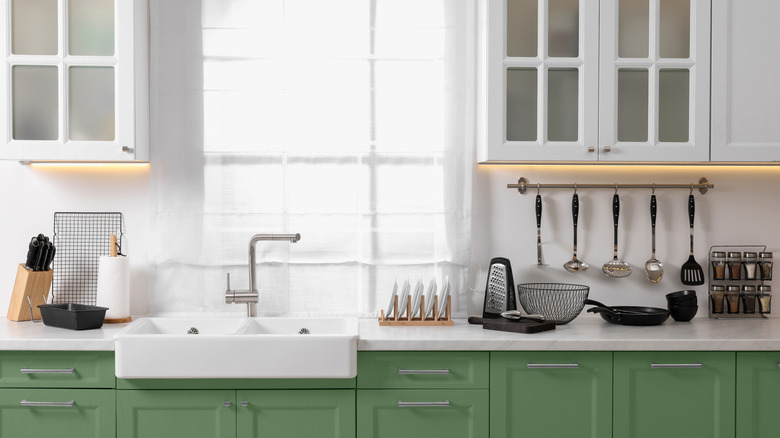 Stylish kitchen with white upper cabinets, green lower cabinets, and a farmhouse sink.