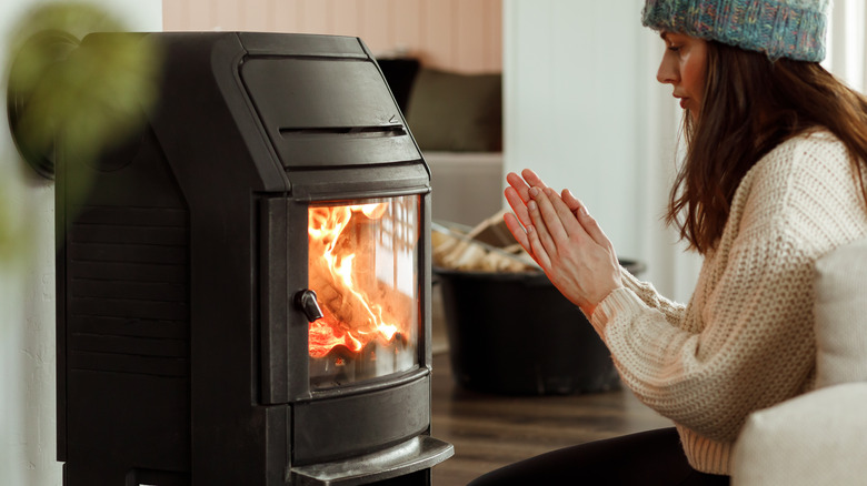 woman sitting next to wood burning stove