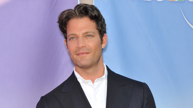 Nate Berkus smiling in front of purple-blue backdrop