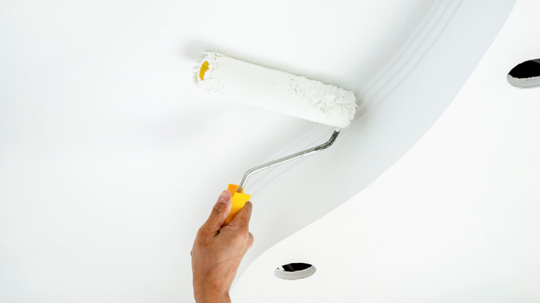 Person painting ceilings with white paint