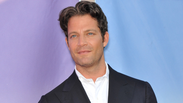 Nate Berkus smiling in front of purple-blue backdrop