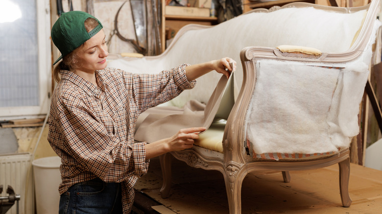 Woman reupholstering sofa in a workshop