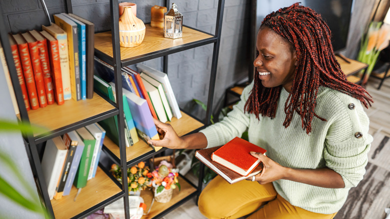 woman placing books on bookshelf