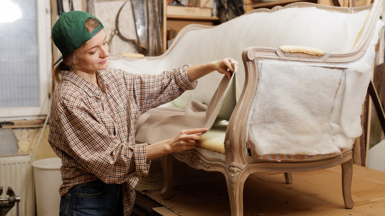 Woman reupholstering sofa in a workshop