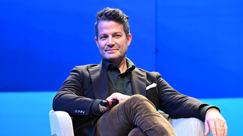 Nate Berkus holds a microphone while onstage at an event