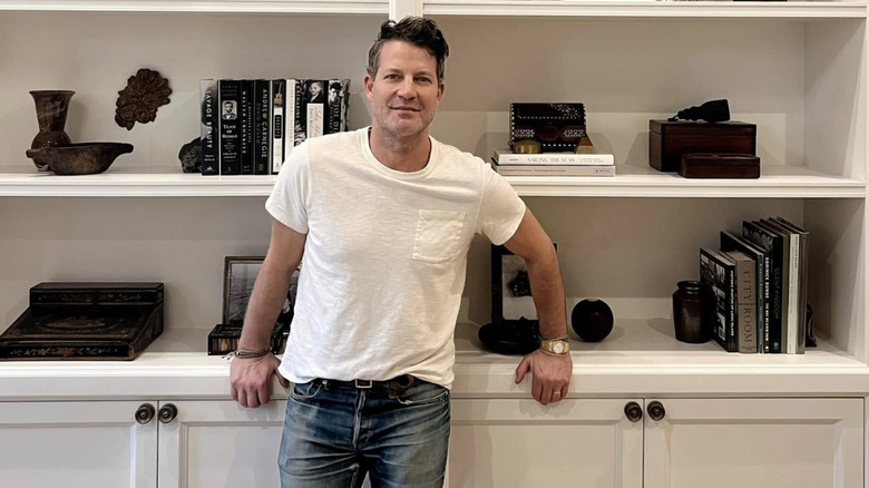 Nate Berkus in front of a bookcase filled with vintage items.