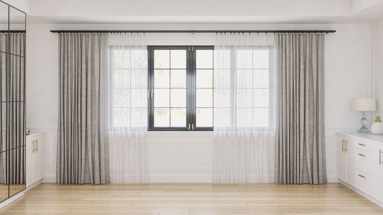 Front view of a cozy retro-chic elegant unfurnished interior with low white hardwood cabinets on both sides, a large and high mirror cabinet in front of a white wood paneled wall with moldings and decoration.