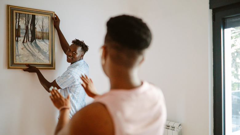 Couple hanging art on wall