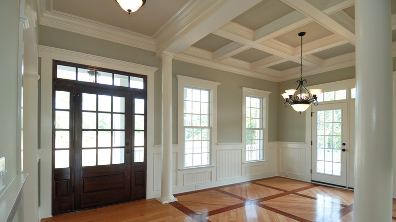 A large, empty dining room with sage green walls and white molding
