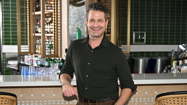 Nate Berkus smiling and leaning on a counter in front of a bar