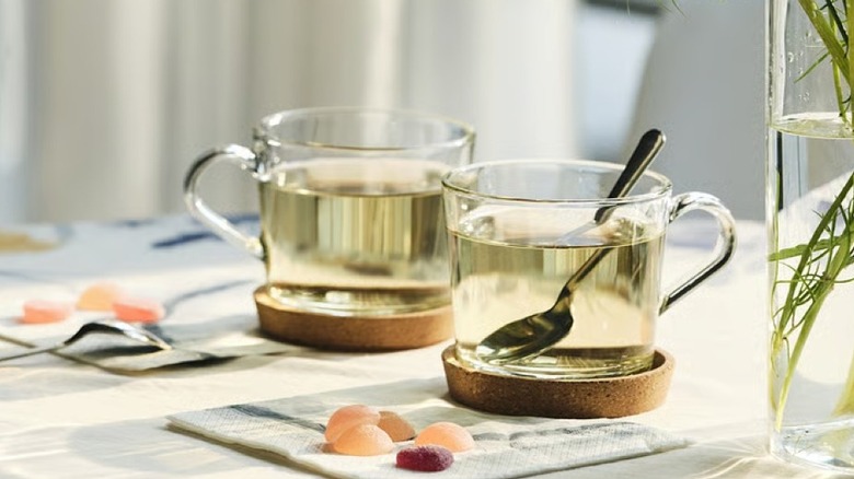 Two glass teacups on cork coasters on a table
