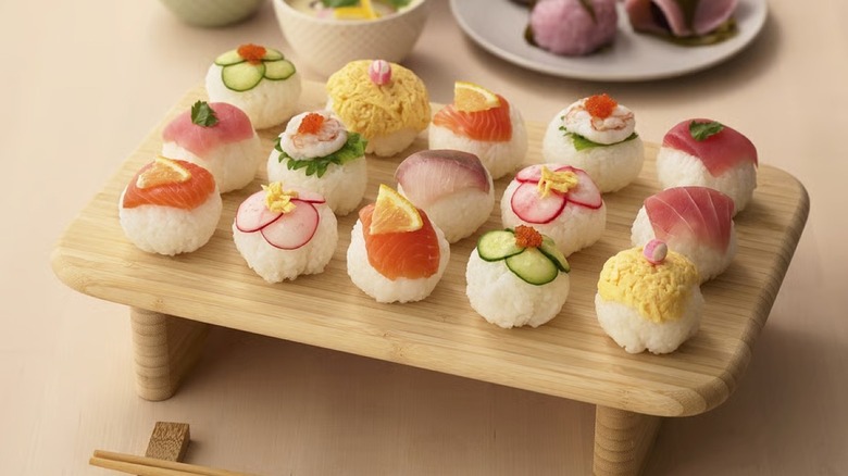 An elevated wood cutting board holding sushi appetizers