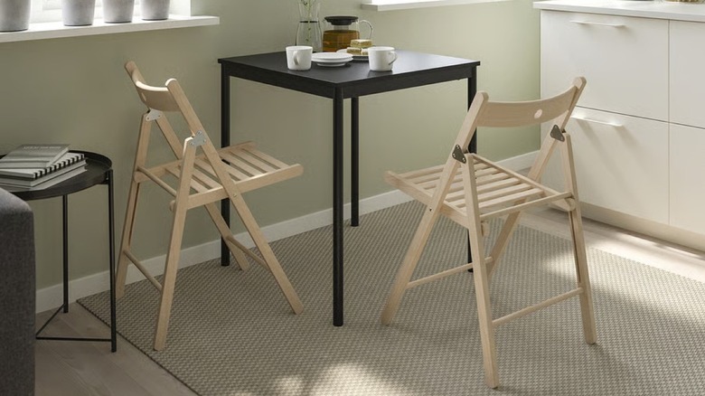 Two wooden IKEA folding chairs at a black table