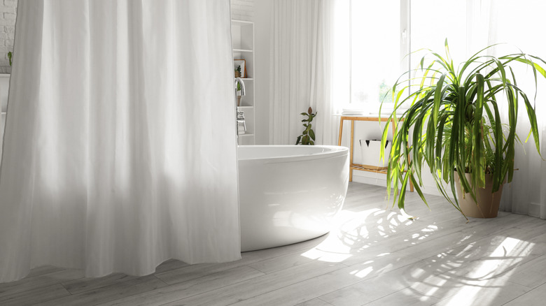 A white bathroom with a shower curtain and basket.