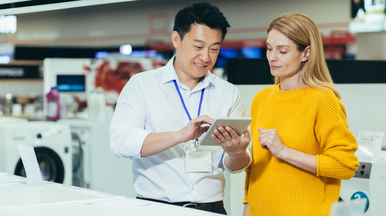 A woman is speaking with a salesperson in an appliance store