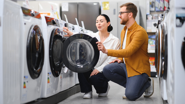 A young couple is looking at washing machines in a store