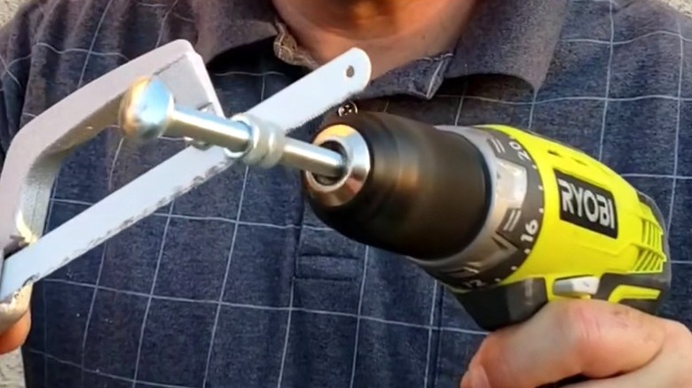 Person cutting bolt with drill and hacksaw