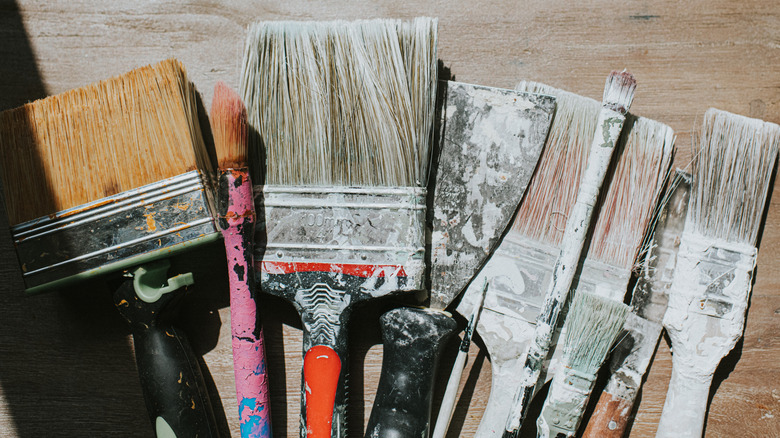 A bunch of used standard size paintbrushes on a table