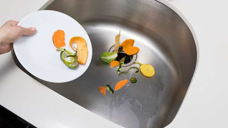Woman putting food scraps into garbage disposal
