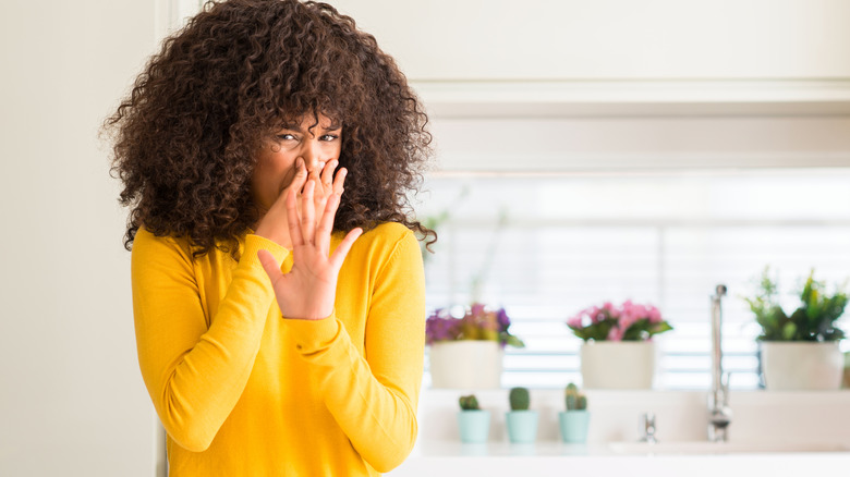 Woman holding nose in stinky kitchen