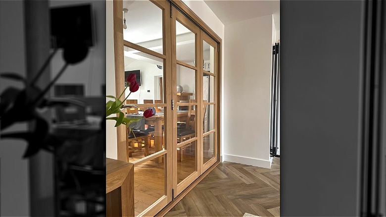 A dining room with table and chairs separated by a folding glass partition to the kitchen.