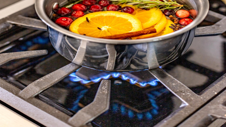 A simmer pot with whole cranberries, rosemary sprigs, orange slices, and cinnamon sticks.