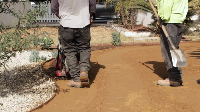 Workers compacting decomposed granite driveway.