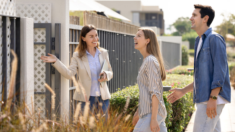 realtor showing home to couple outside