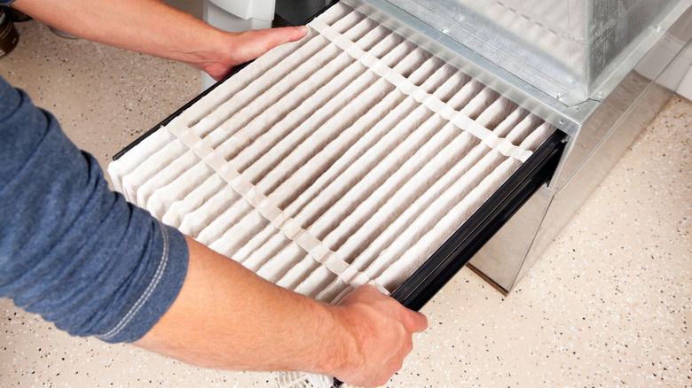 A person changing their furnace filter