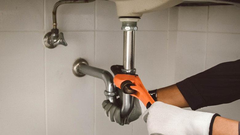 A person fixing a sink pipe